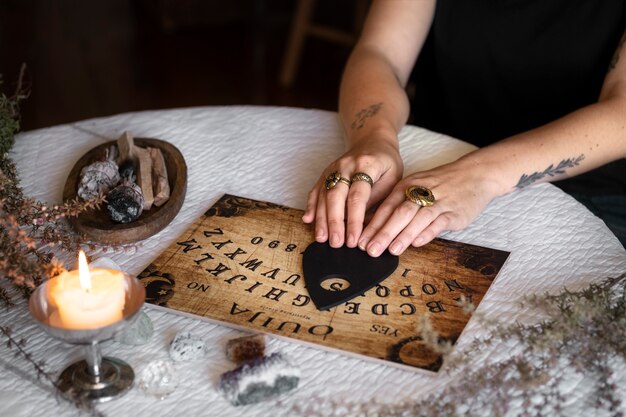 Hands using wooden ouija board high angle