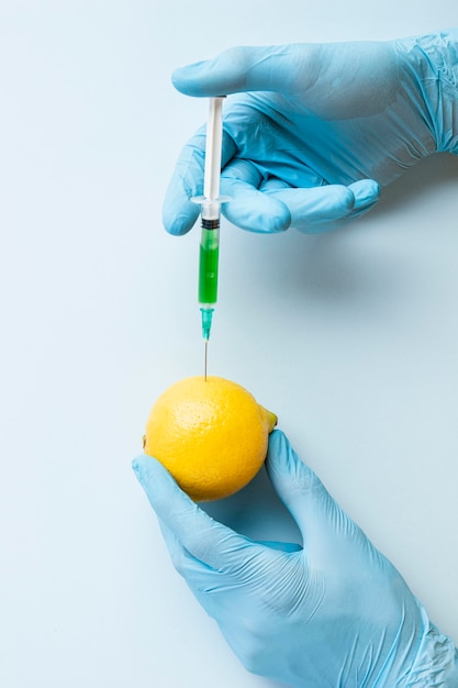 Free photo hands wearing gloves and injecting chemicals in a lemon