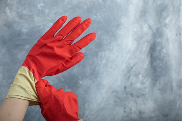 Hands wearing red protective gloves on marble.