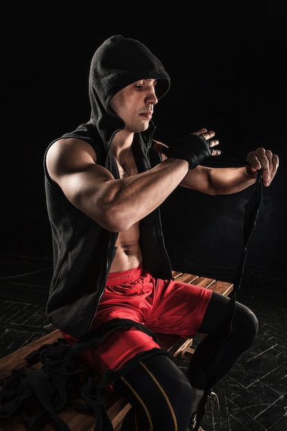 The hands with bandage of muscular man training kickboxing  on black