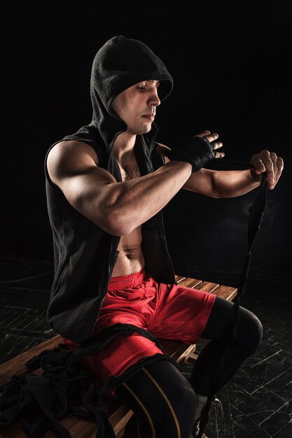 The hands with bandage of muscular man training kickboxing  on black