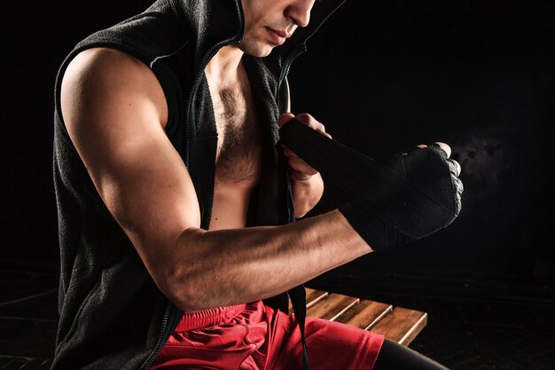 hands with bandage of muscular man training kickboxing  on black