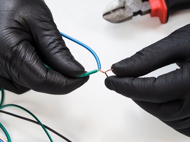 Hands with black gloves connecting wires