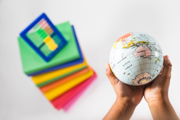 Hands with globe in studio with books and abacus 