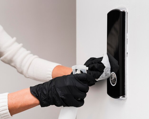 Free photo hands with gloves disinfecting door bell