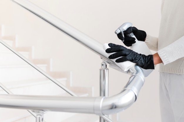 Hands with gloves disinfecting hand rail