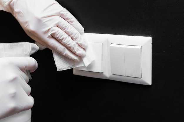 Hands with gloves disinfecting light switches