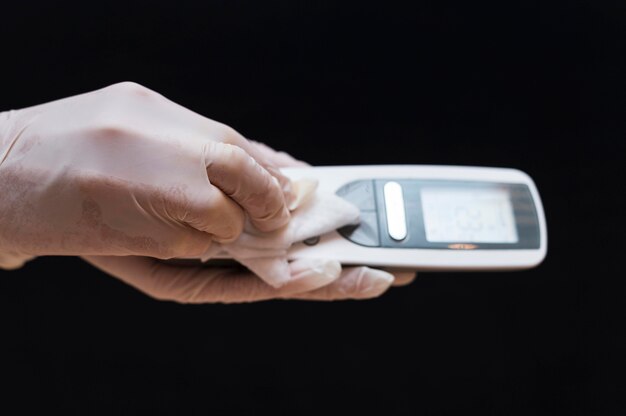 Hands with gloves disinfecting telephone