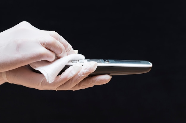 Hands with gloves disinfecting telephone