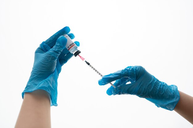 Hands with gloves holding syringe and vial