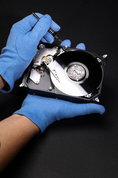 Hands with gloves repairing hard drive high angle