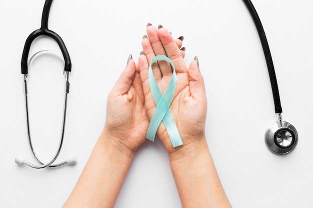 Hands with light blue ribbon near stethoscope