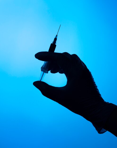 Hands with protective glove holding a covid vaccine