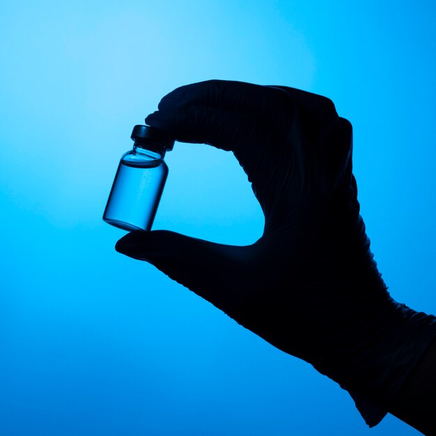 Hands with protective glove holding a covid vaccine