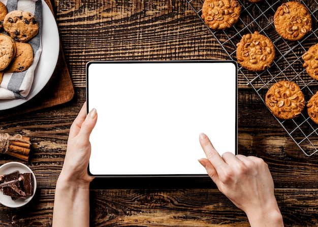 hands with tablet and Delicious cookies beside