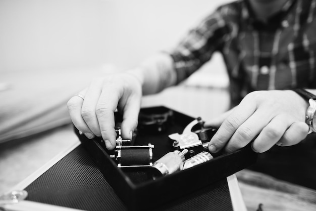 Hands with tattoo machine at tattoo master