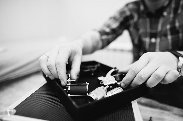 Hands with tattoo machine at tattoo master