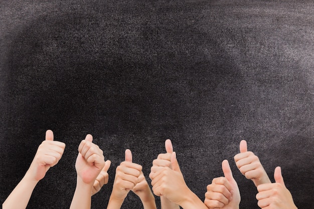 Hands with thumbs up gesture against a blackboard