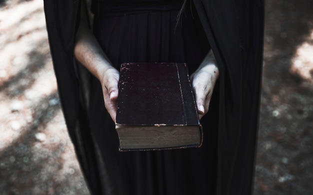 Hands of woman in black dress holding old book