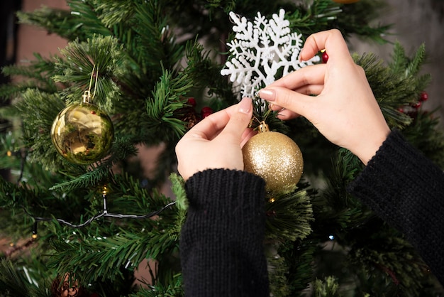 Hands of woman hanging a Christmas ball on a Christmas tree . High quality photo