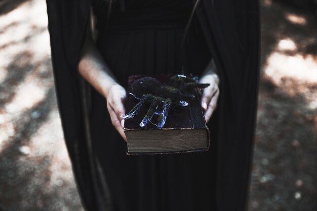 Hands of woman holding book with spider on top