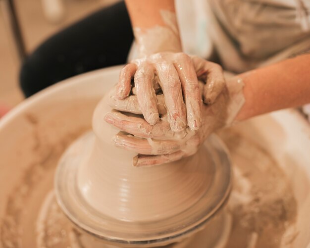 陶器のホイールに粘土のボウルを作る過程で女性の手