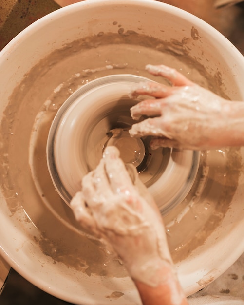 陶器のホイールに粘土のボウルを作る過程で女性の手