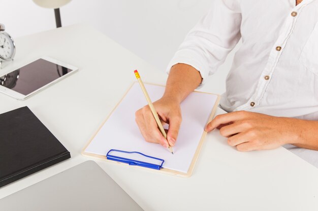 Hands writing on clipboard