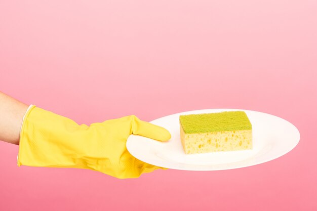 Руки в желтых защитных перчатках моют тарелку