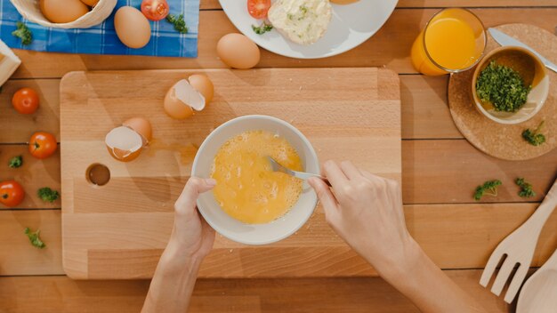 세라믹 그릇에 계란을 크래킹하고 오믈렛 요리 젊은 아시아 여자 요리사의 손에