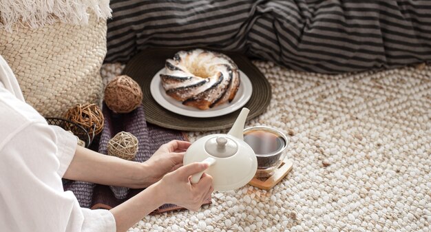 Hands of a young woman pour tea from a teapot. Preparing Breakfast in a cozy home atmosphere.