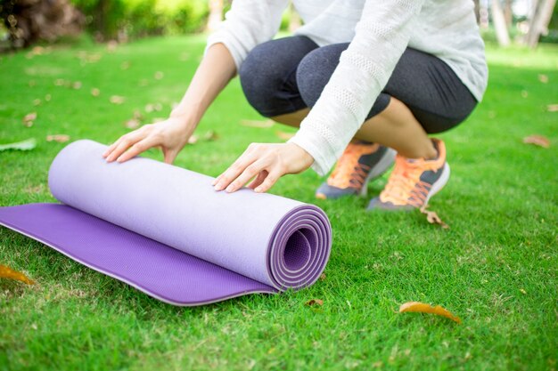 Hands of young woman rolling out exercise mat