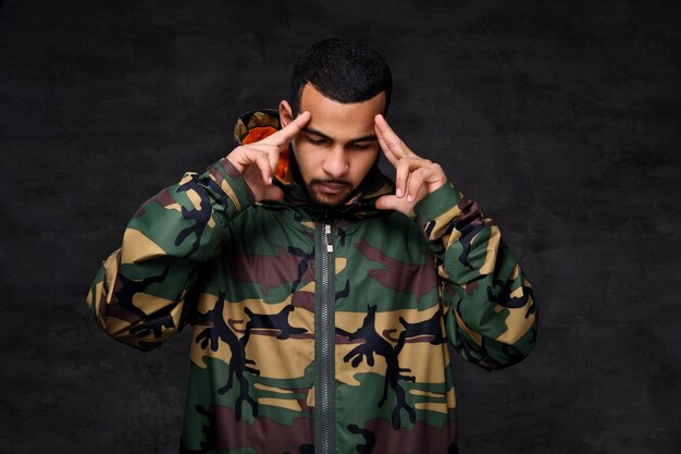 Handsome African-American guy wear military jacket. Isolated over dark background.