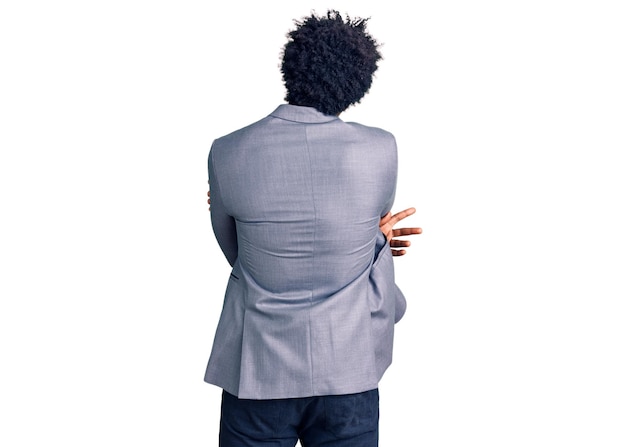 Free photo handsome african american man with afro hair wearing business jacket hugging oneself happy and positive from backwards self love and self care