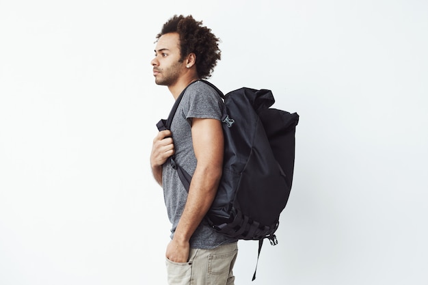Handsome african man with rucksack standing in profile