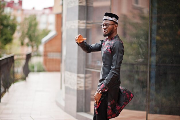 Handsome afro american man wearing traditional clothes cap and eyeglasses in modern city