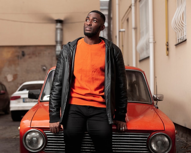 Handsome afroamerican man sitting on car