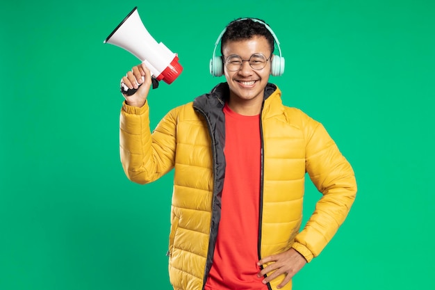 緑の背景にメガホンを持って笑っているハンサムなアジアの若い男