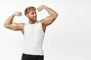 Free photo handsome athlete looking strong flexing biceps showing his strong muscles arms smiling pleased workout and doing fitness exercises white background