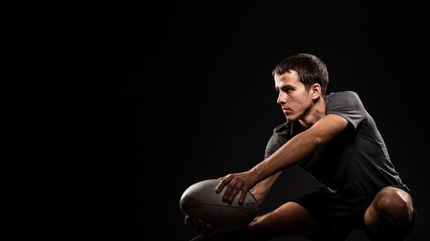Красивый спортивный мужской игрок в регби, держащий мяч с копией пространства