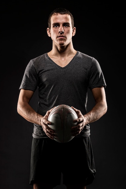 Красивый спортивный мужской игрок в регби, держащий мяч