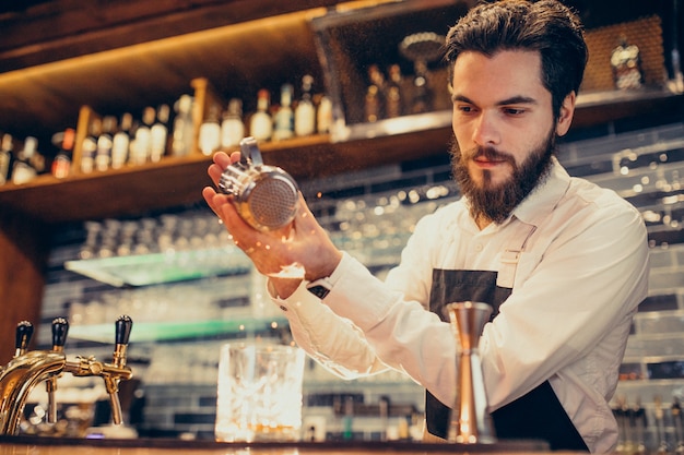 Красивый бармен делает пить и коктейли на прилавке