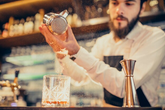 Handsome bartender making drinking and cocktails at a counter