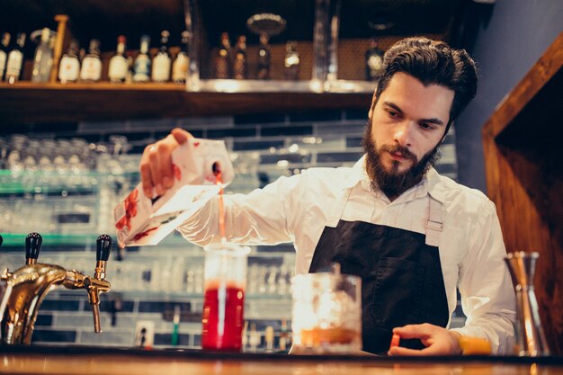 Handsome bartender making drinking and cocktails at a counter