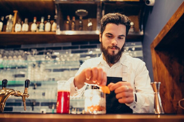 Handsome bartender making drinking and cocktails at a counter
