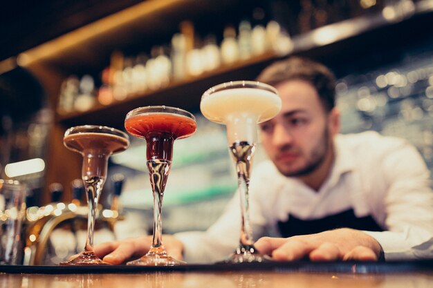 Handsome bartender making drinking and cocktails at a counter