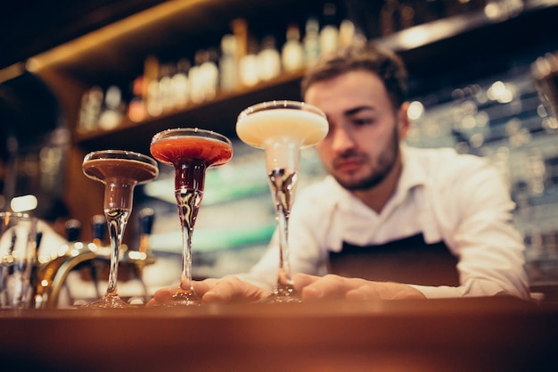 Foto gratuita barista bello che fa bere e cocktail ad un contatore