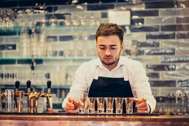 カウンターで飲むとカクテルを作るハンサムなバーテンダー男