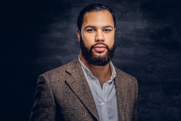 Handsome bearded African-American businessman in a brown classic jacket. Isolated on a dark background.