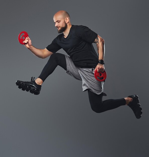 Handsome bearded athlete in sportswear jumping in a studio. Isolated on a gray background.